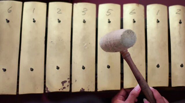 close up of a gamelan player striking Saron