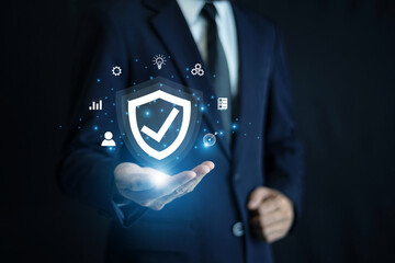 Businessman holding a cybersecurity protection shield hologram to represent data privacy, online security, and digital transformation in modern business.