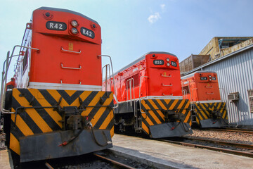 Three orange diesel locomotives, including R42, R55, and R34, are parked on tracks at the historic Changhua Roundhouse in Changhua City, Taiwan, under a clear sky.