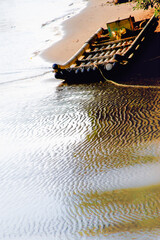 A bamboo raft rests on a sandy shore with rippling water, captured at sunset on October 7, 2012, in Miaoli County, Taiwan.