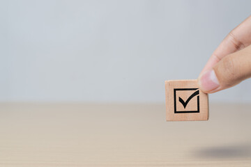 Business and quality assurance concept. Hand arranging checkmark icon on wooden block representing document approval and project validation