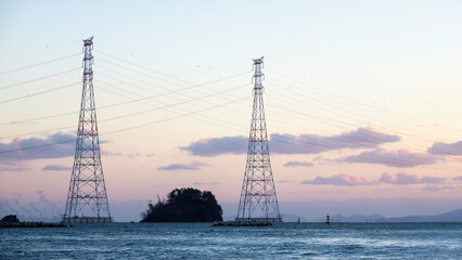 electricity pylon on the sea during sunset