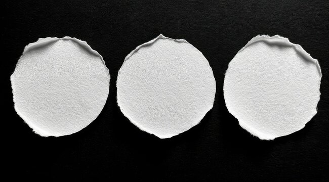 Three round, torn pieces of white paper are arranged horizontally against a solid black background, creating a simple yet visually striking image