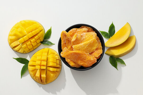 A bowl of dried mango chips with fresh sliced mango
