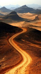 Breathtaking panoramic view of winding desert road passing through golden dunes with rugged mountains and distant hills under clear sky du daylight