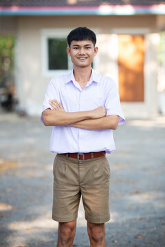 Thai boy student in official Thai school uniform (khaki or brown shorts), properly dressed, stand firmly with arms folded across chest