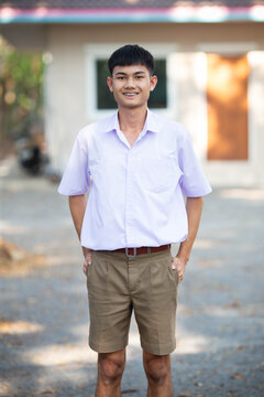 Thai boy student in official Thai school uniform (khaki or brown shorts), properly dressed, stand firmly with two hands in pockets