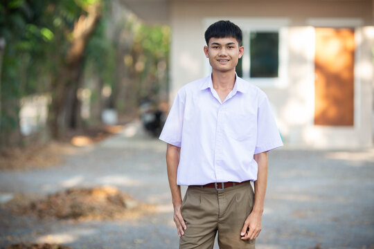 Thai boy student in official Thai school uniform (khaki or brown shorts), properly dressed, stand firmly with only one hand in pocket, horizontal image
