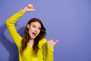 Joyful young woman in vibrant sweater expressing excitement against a purple backdrop embodying...