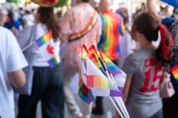 Blurred image of a crowd marching with rainbow flags at a Canadian Pride parade to celebrate Pride...