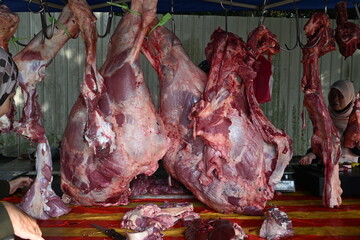 A close-up view of freshly slaughtered cow carcasses hanging on metal hooks during the week of Eid al-Adha, also known as Hari Raya Haji, a significant Islamic festival in Malaysia.