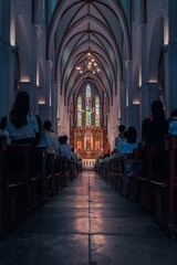 Fototapeta premium The majestic interior of a cathedral with high gothic arches, ornate chandeliers, and stunning stained glass windows at the altar. 