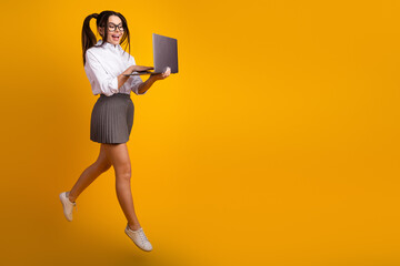 Energetic Young Woman with Laptop Against Vibrant Yellow Background, in Casual yet Trendy School...