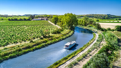 Aerial drone view of houseboat in Canal du Midi from above, family travel by boat, vacation cruise trip in Southern France