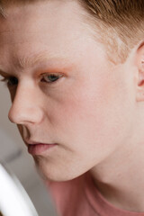 Man Looking into Vanity Mirror Preparing for Skincare Routine Vertical Extreme Close Up
A young man...