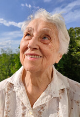 Positive senior woman watering decorative plants on balcony