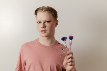 A Medium shot of a Man Holding Makeup Brush Posing with Finished Look
A young man poses confidently...