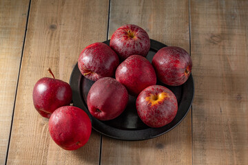 Some vibrant red apples rest on a rustic wooden background, highlighting their fresh appeal. Perfect for themes related to healthy eating, natural food, or autumn harvest.