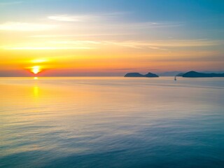 Obraz premium Serene sunset over calm ocean with distant islands