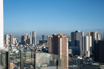 Fototapeta premium The cityscape of Manila skyline with high-rise buildings surrounded by lush greenery outdoor at daytime with blue sky.on the rooftop of a hotel during a holiday in the Philippines in South East Asia.