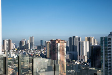 Obraz premium The cityscape of Manila skyline with high-rise buildings surrounded by lush greenery outdoor at daytime with blue sky.on the rooftop of a hotel during a holiday in the Philippines in Asia.