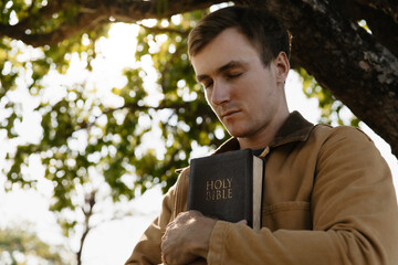 Young man holding a Bible and praying for god.