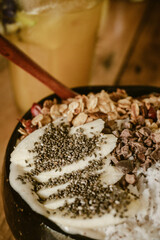 Close up of a delicious healthy smootie bowl served in a coconut with chia seed, bananas, coconut rasp, granola and flowers inside a cafe during a summer holiday on Siargao island in the Philippines.