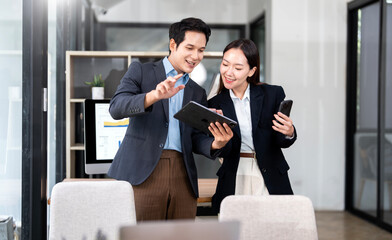 Portrait of two business colleagues talking and discussing together, using digital tablet and ...