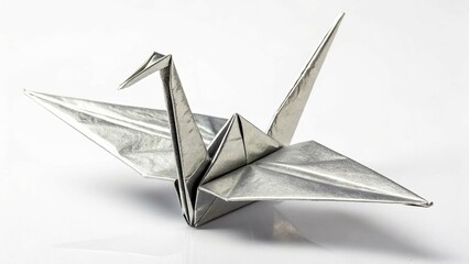 A shiny, silver origami crane is centered on a white surface 