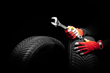 Winter car tires service and thumbs up hands of mechanic with wrench, screwdriver on black background