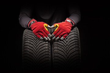Car tire service and hands of mechanic holding new tyre on black background with copy space for text