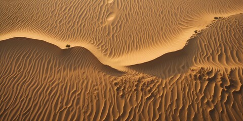 Sand dune patterns captured from aerial view creating abstract golden wave texture.