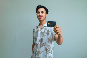 Portrait of a smiling young Asian man in summer clothes showing a card product, perfect for advertisement with a clear background