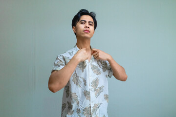 Portrait of a young Asian man wearing summer clothes, holding his collar with an arrogant, haughty expression on a clear background