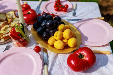 A plate of apricots and plums on a table beautifully decorated with vegetables.