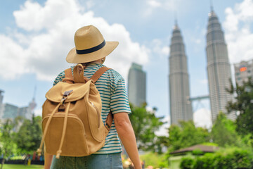Female tourist in hat with backpack enjoying cityscape, Malaysia
