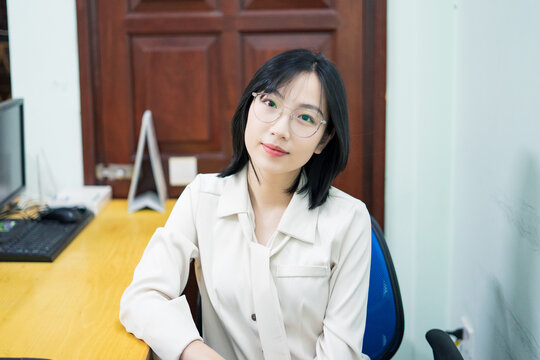 Young woman sitting confidently at her workspace in a well-lit office, focused on her next task during a busy workday in Vietnam