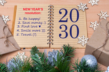 2030 New Year's Resolution - Hand holding a pen and writing down plans for the new year: be happy,...
