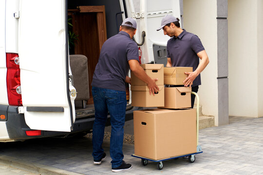 Male delivery persons loading boxes in moving van