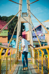 Indonesian Man Posing on Yellow Bridge in Colorful Kampung Warna-Warni, Malang