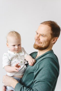 Father holding his son indoors, both smiling and looking at the camera