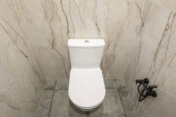 modern toilet with stone-patterned walls, a dark-grey tiled floor, and a bidet