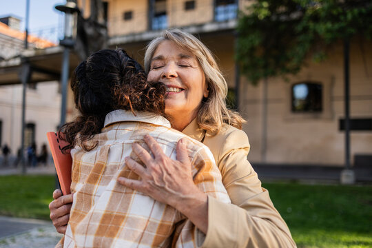 University professor and student hugging outdoors on campus