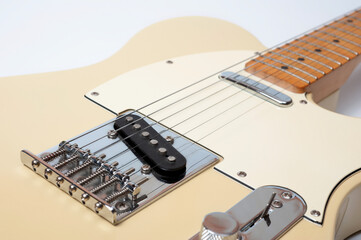 Six-string electric guitar, with a cream-colored wooden body and chrome-plated fittings.