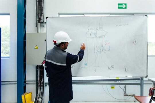 Engineer writing on a whiteboard in an industrial workshop