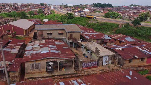 Jib up of the outskirts of a larger city in Ibadan, Nigeria. Cars drive over a highway adjacent to the slums
