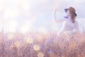 Summertime background, a beautiful female model posing in a field against a background of sun glare...