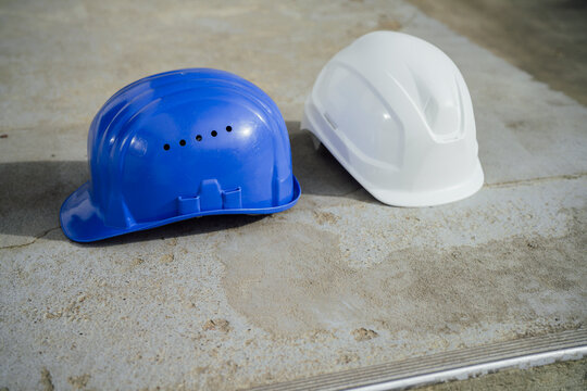Blue and white hard hats on a cement surface outdoors