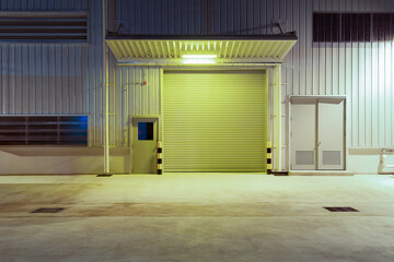 Exterior of industrial building at night. Construction for factory or warehouse. Include shutter door at front. Nobody empty space on concrete floor suit for product display or industrial background.