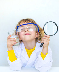 A child examines water with a magnifying glass. Selective focus.